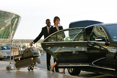 A man and a woman wearing black suit about to sit inside of a car
