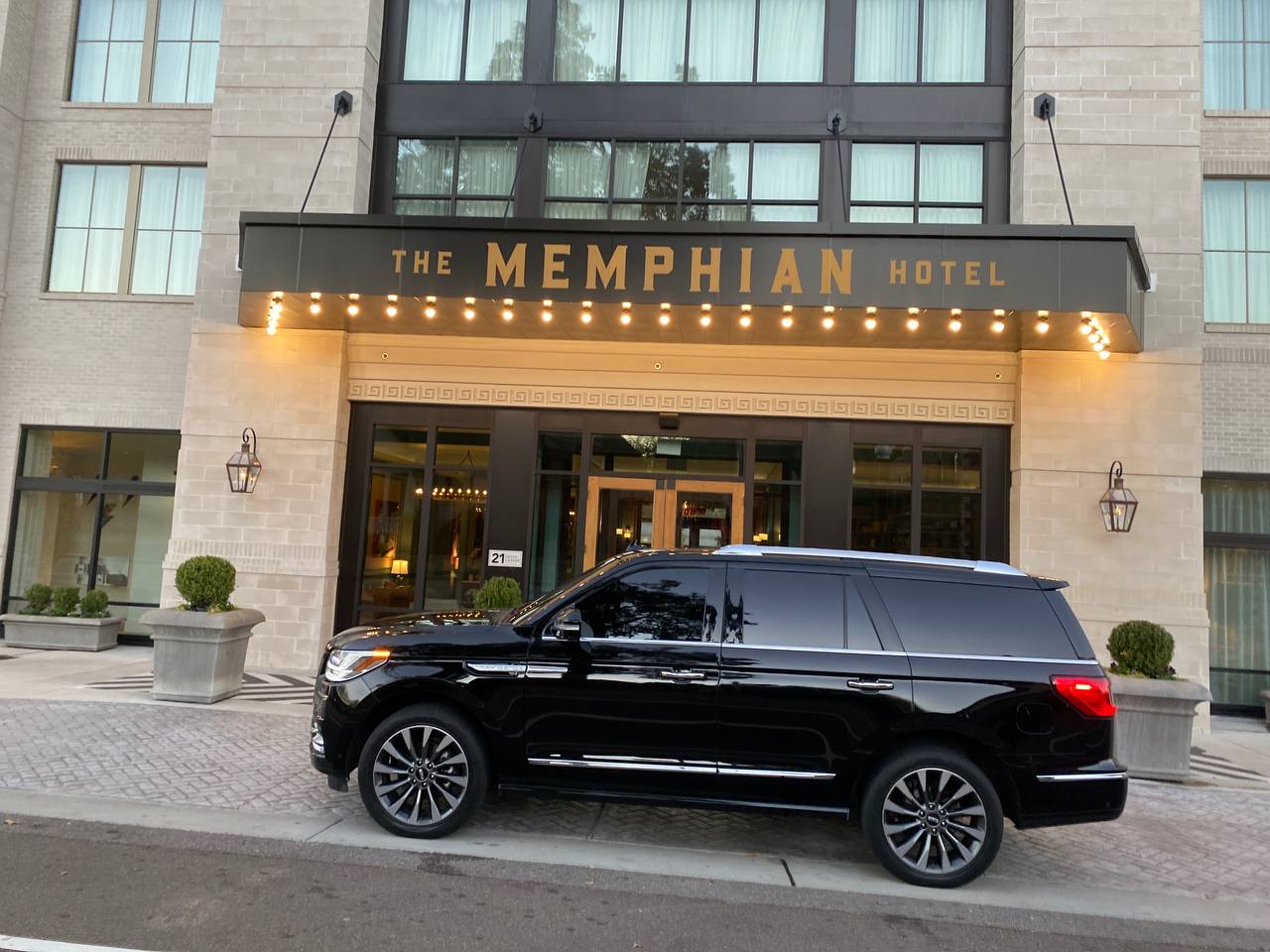 A black suv parked in front of the entrance to a hotel.