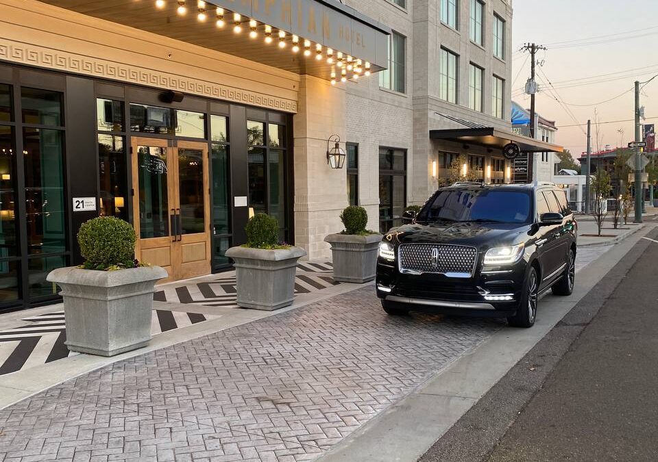 A car parked on the side of a street near a Hotel.